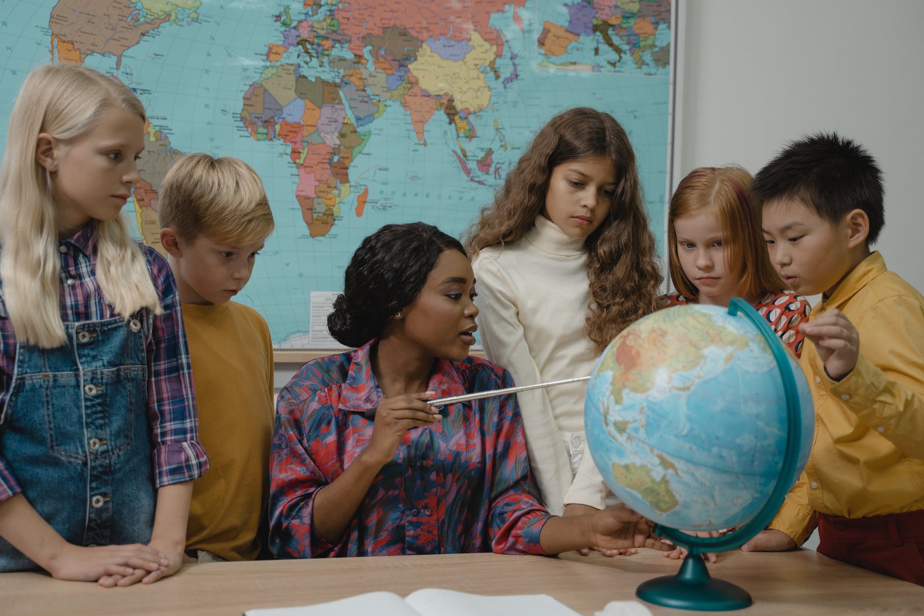 teacher teaching students about geography using a globe